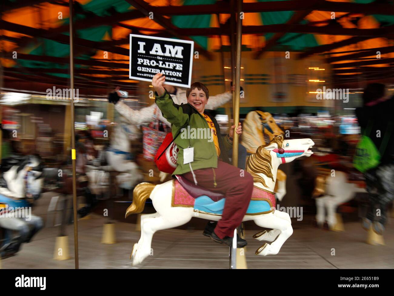 An anti-abortion demonstrator rides a carousel in the National Mall in Washington January 23, 2012. Nearly 100,000 protesters marched from the National Mall to the U.S. Supreme Court today marking the 39th anniversary of the Court's landmark Roe v. Wade decision on abortion. REUTERS/Kevin Lamarque (UNITED STATES - Tags: CIVIL UNREST ANNIVERSARY) Stock Photo