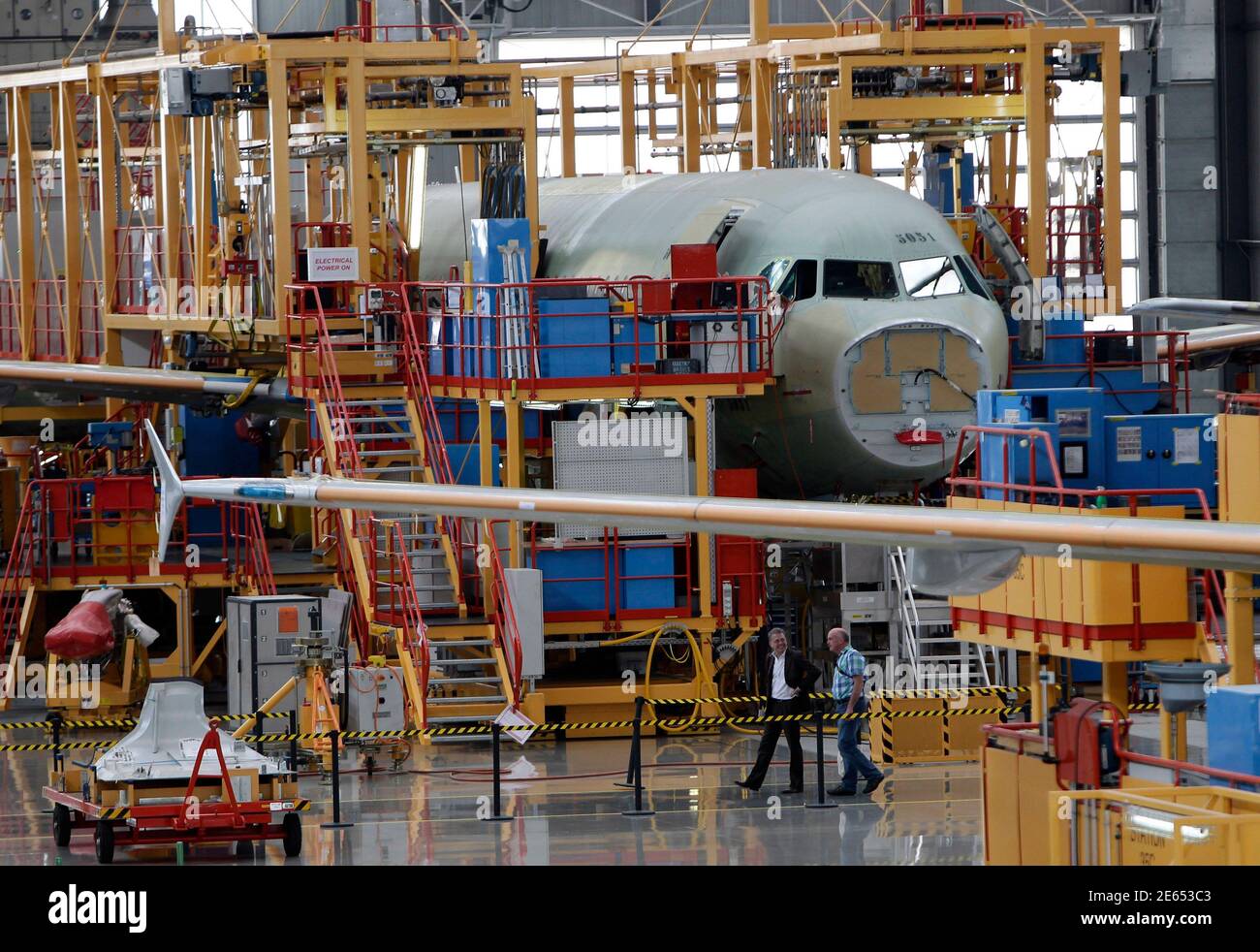 Vistors walk past an A320 plane under construction at the final assembly line of Airbus factory in Tianjin municipality, June 13, 2012. European planemaker Airbus said its total gross aircraft orders stood at 149 from January to May, helped by a contract recently signed with Air Lease for 36 planes. REUTERS/Jason Lee (CHINA - Tags: BUSINESS TRANSPORT) Stock Photo