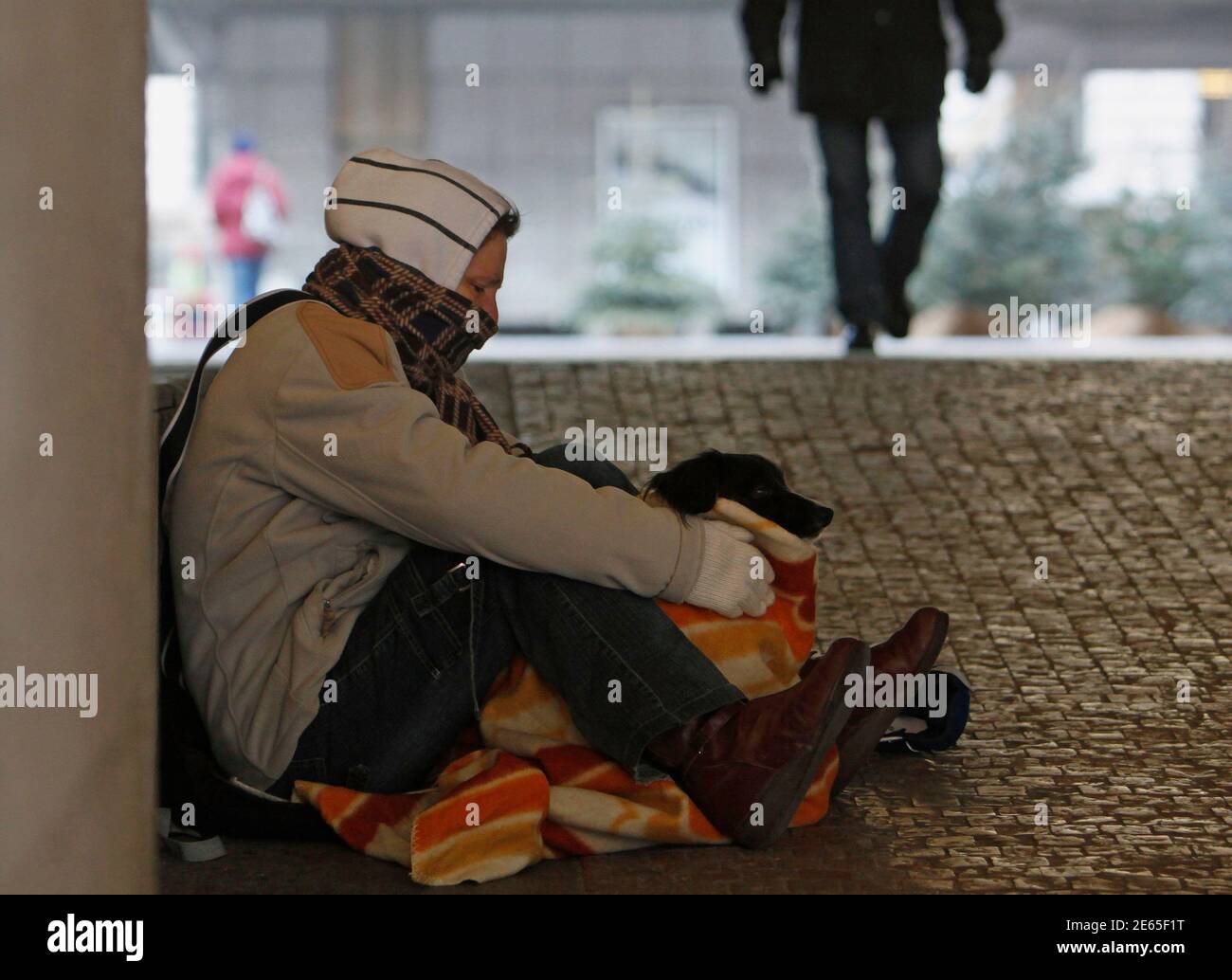 A beggar and his dog sit on a sidewalk as temperatures dropped to as low as  minus 11 degrees Celsius (12.2 degrees Fahrenheit) in Prague February 6,  2012. REUTERS/David W Cerny (CZECH