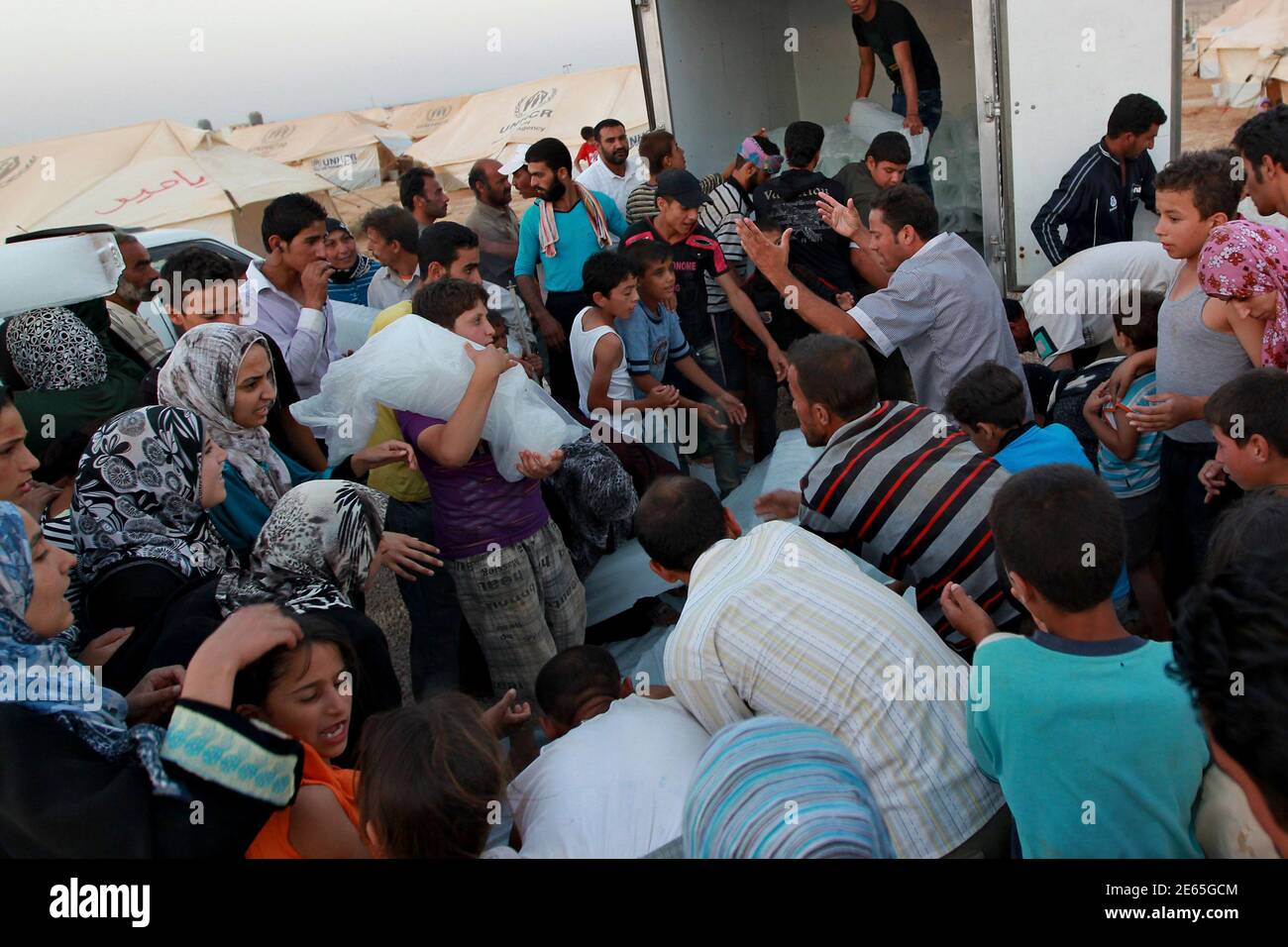 Syrian refugees wait to receive ice at the Al Zaatri refugee camp in the Jordanian city of Mafraq, near the border with Syria, July 31, 2012. Jordan opened the camp with 2,000 tents on Sunday, to accommodate an expected new influx of refugees near the border. Diplomats say around 115,000 Syrians have fled their country, mostly to Turkey, Lebanon and Jordan, to escape the 17-month rebellion against President Bashar al-Assad. The Jordanian authorities say around 130,000 Syrians have come to Jordan since the uprising began, but diplomats say not all of them are classified as refugees. REUTERS/Muh Stock Photo