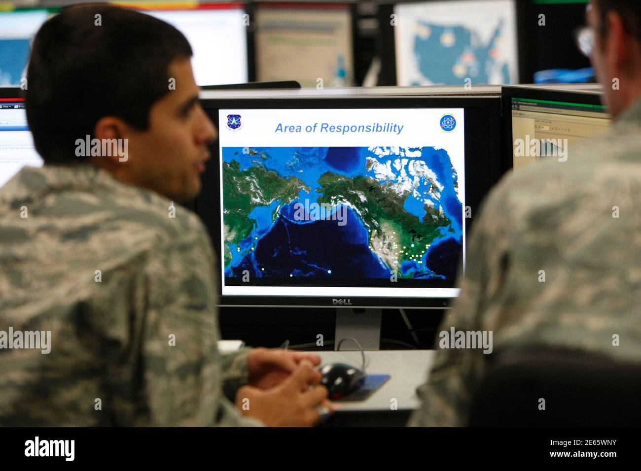 2Lt William Liggett (L) talks with a colleague as a map is displayed on one of the screens at the Air Force Space Command Network Operations & Security Center at Peterson Air Force Base in Colorado Springs, Colorado July 20, 2010. U.S. national security planners are proposing that the 21st century's critical infrastructure -- power grids, communications, water utilities, financial networks -- be similarly shielded from cyber marauders and other foes. The ramparts would be virtual, their perimeters policed by the Pentagon and backed by digital weapons capable of circling the globe in millisecon Stock Photo