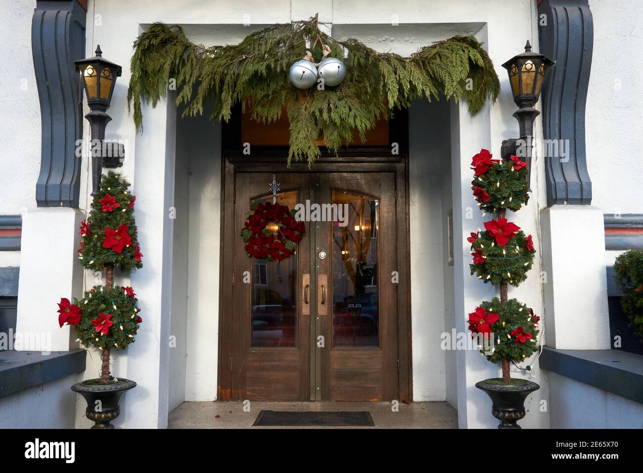 Front entrance of an old apartment building decorated with a Christmas wreath, green cedar boughs, and topiary Stock Photo