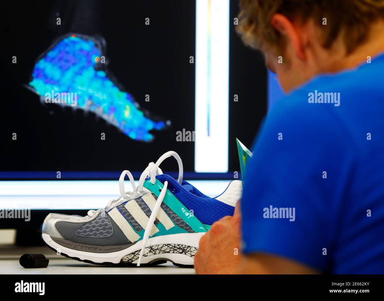 An engineer adjusts test marks on an Adidas running shoe at the Adidas  innovation laboratory in Herzogenaurach May 7, 2012. U.S. market leader  Nike and German rival Adidas are locked in their