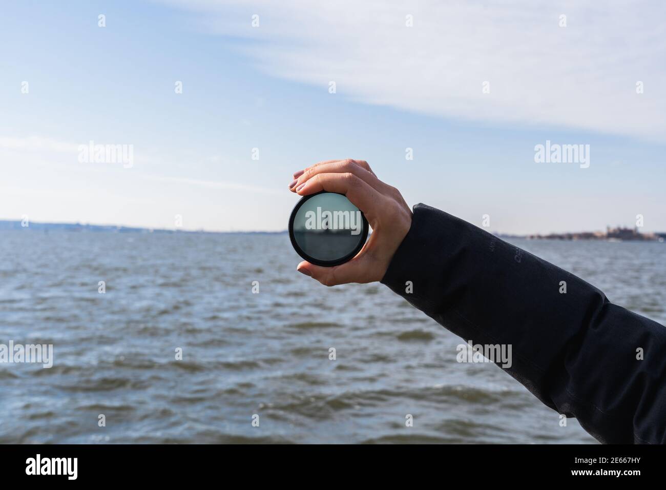 A photo of a hand holding up a lens filter, with the Statue of Liberty