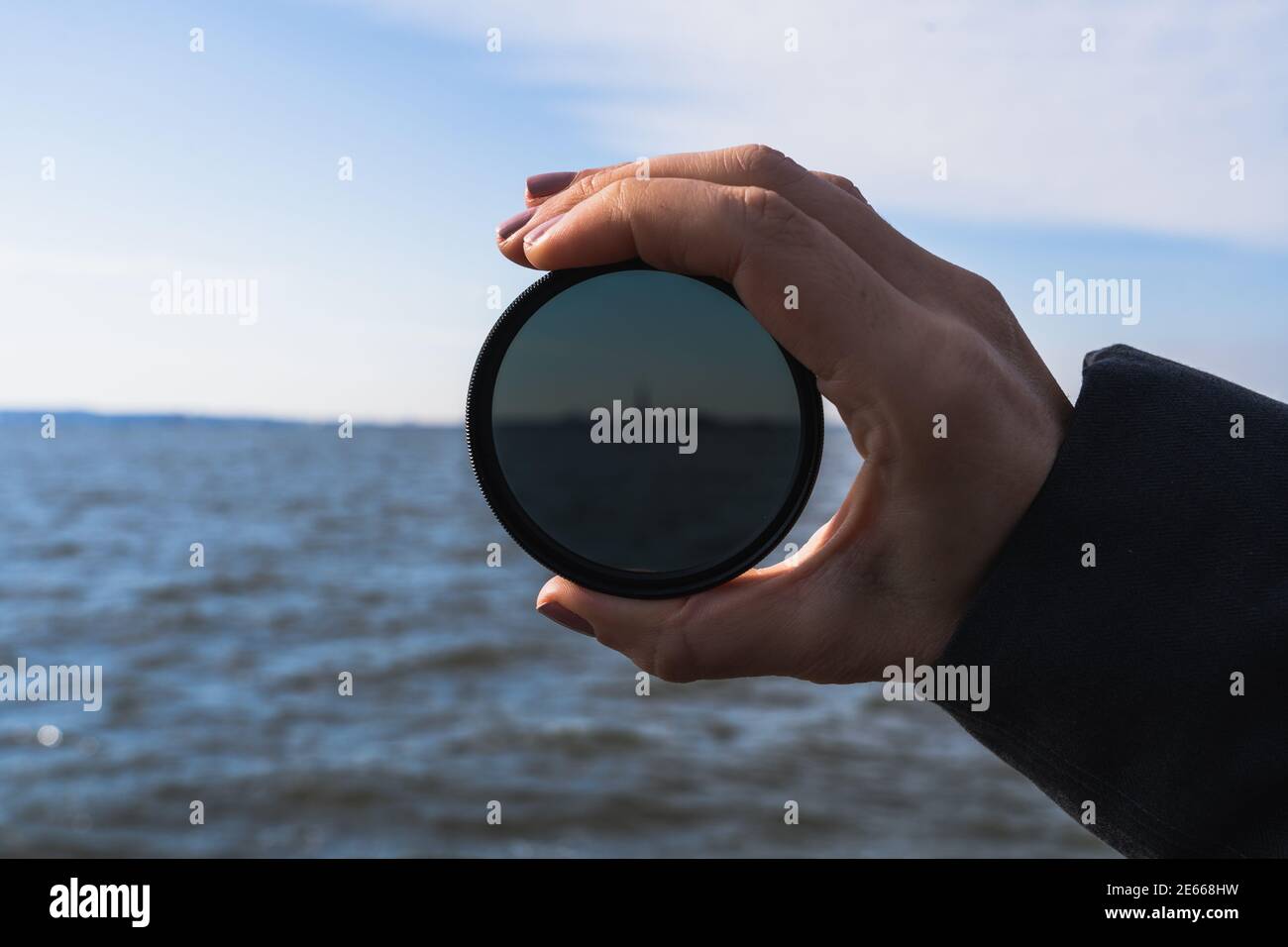 A photo of a hand holding up a lens filter, with the Statue of Liberty
