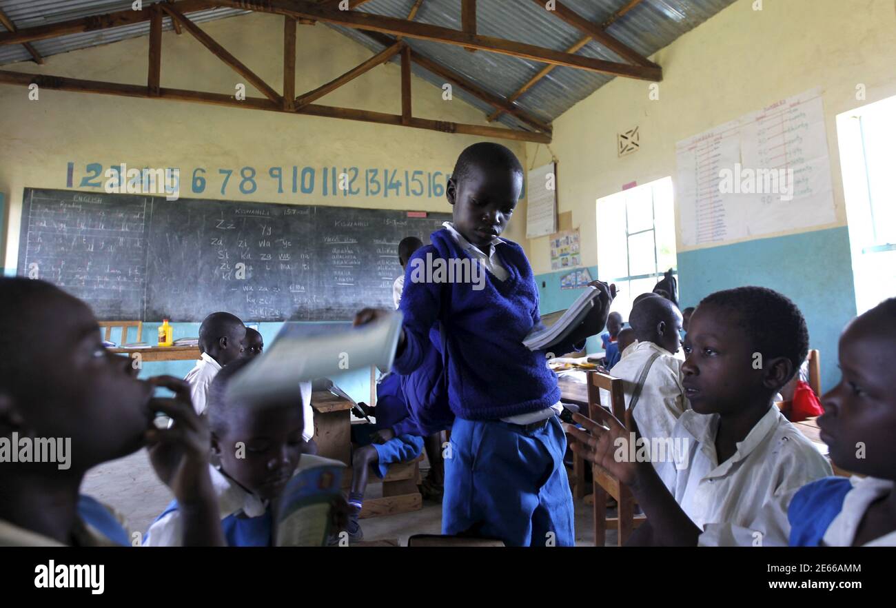 Seven year old Barack Obama, named after U.S. President Barack Obama distributes books to his classmates at the Senator Obama primary school in Nyangoma village in Kogelo west of Kenya's capital Nairobi, July 16, 2015. Obama visits Kenya and Ethiopia in July, his third major trip to Sub-Saharan Africa after travelling to Ghana in 2009 and to Tanzania, Senegal and South Africa in 2011. He has also visited Egypt, in North Africa, and South Africa for Nelson Mandela's funeral. Obama will be welcomed by a continent that had expected closer attention from a man they claim as their son, a sentiment  Stock Photo