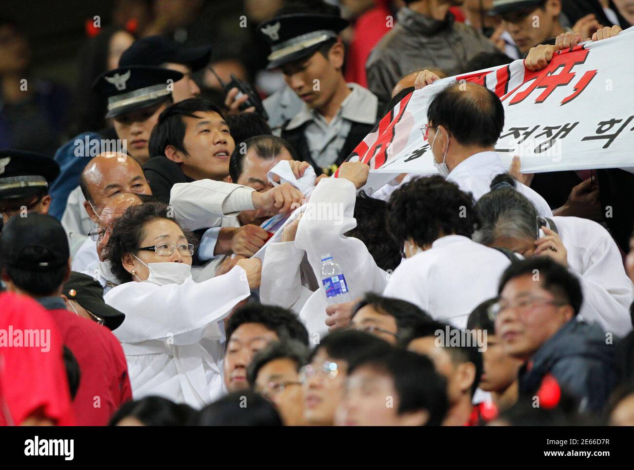 Members (R) of the Association for the Pacific War Victims struggle with police officers as they try to hold an anti-Japan rally demanding full compensation from the Japanese government during a friendly soccer match between South Korea and Japan in Seoul October 12, 2010.  REUTERS/Jo Yong-Hak (SOUTH KOREA - Tags: SPORT SOCCER CIVIL UNREST POLITICS) Stock Photo