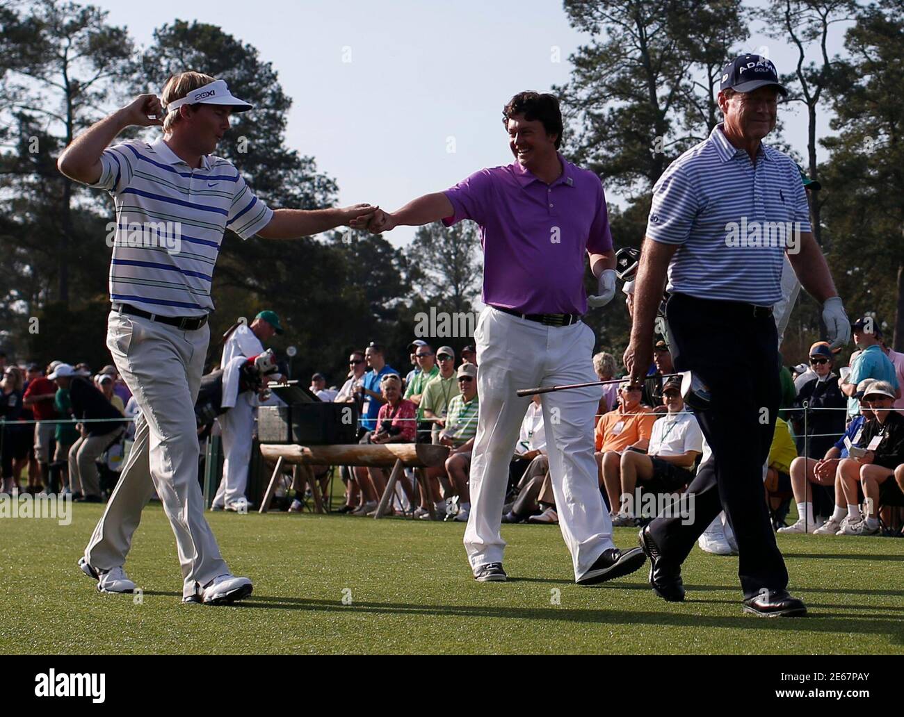 Former champion Tom Watson of the U.S. (R) walks in front of amateurs  Russell Henley (L) and Nathan Smith of the U.S. as they congratulate  themselves after their drives on the first