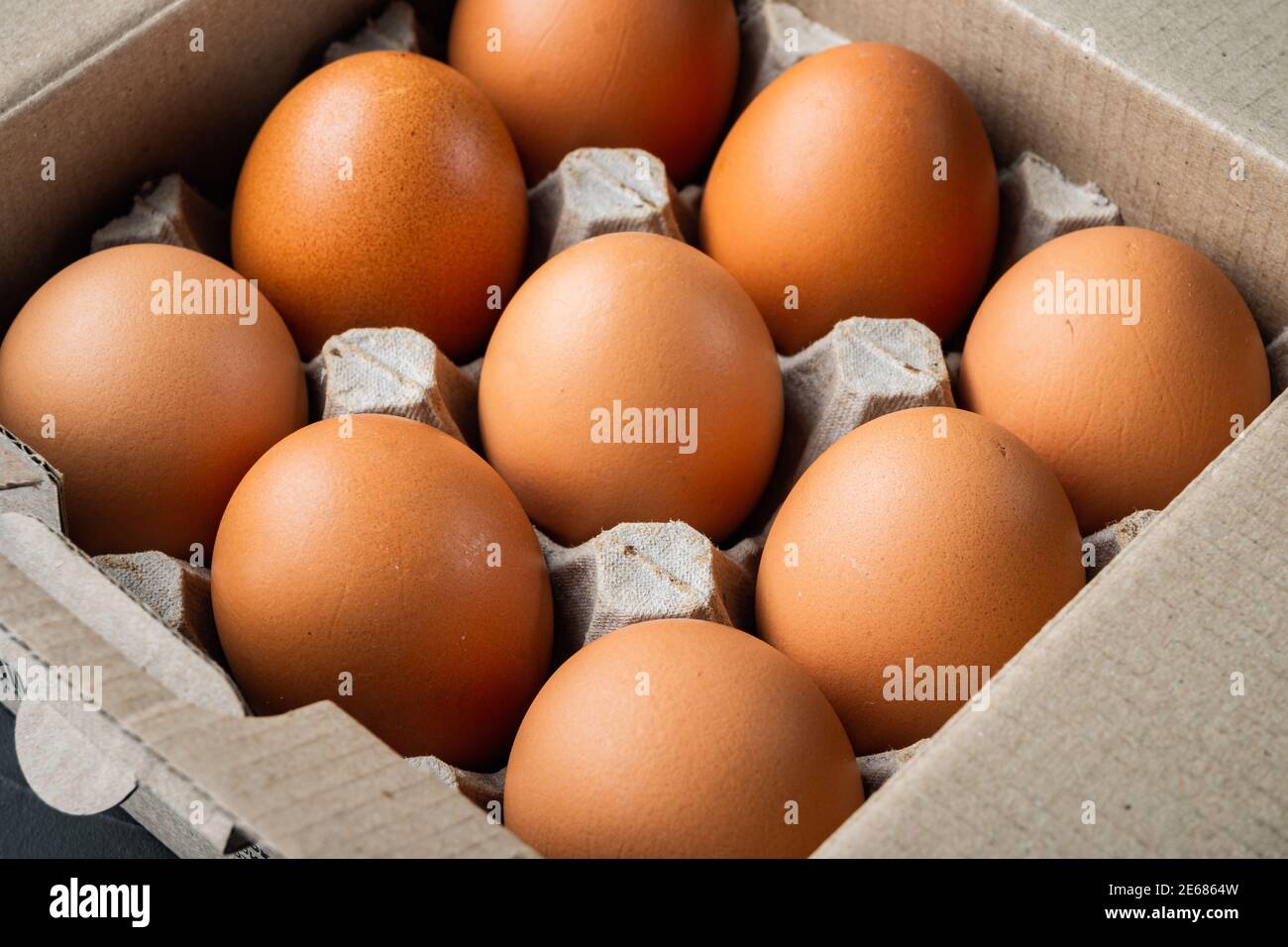 Raw chicken eggs in egg box set, on black background Stock Photo