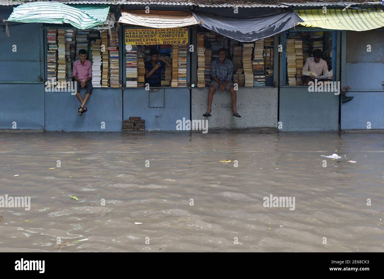 Book sellers wait for customers inside their flooded shops after heavy rainfall in Kolkata, India, July 10, 2015. After drenching India with above-average rains in June, the monsoon has weakened in what is typically the wettest and most crucial month for millions of farmers growing oilseeds, rice, cotton and pulses. Good rainfall this year is key to boosting a rural economy hit by delayed and lower rains last year, as well as keeping a lid on food inflation and giving India's central bank more scope to cut lending rates. REUTERS/Rupak De Chowdhuri Stock Photo