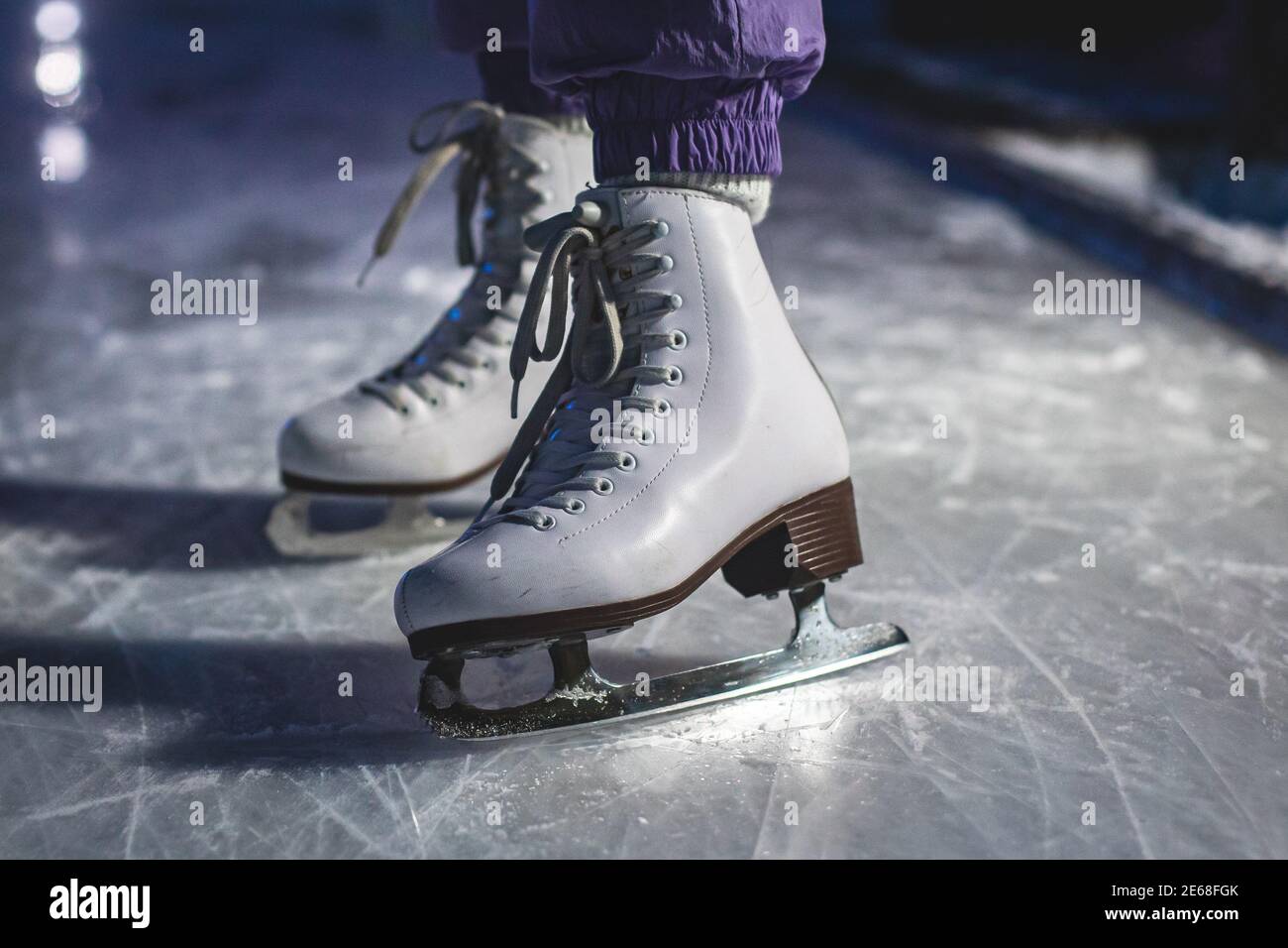 Close up view of new white ice skates boots on rink in motion, girl ice