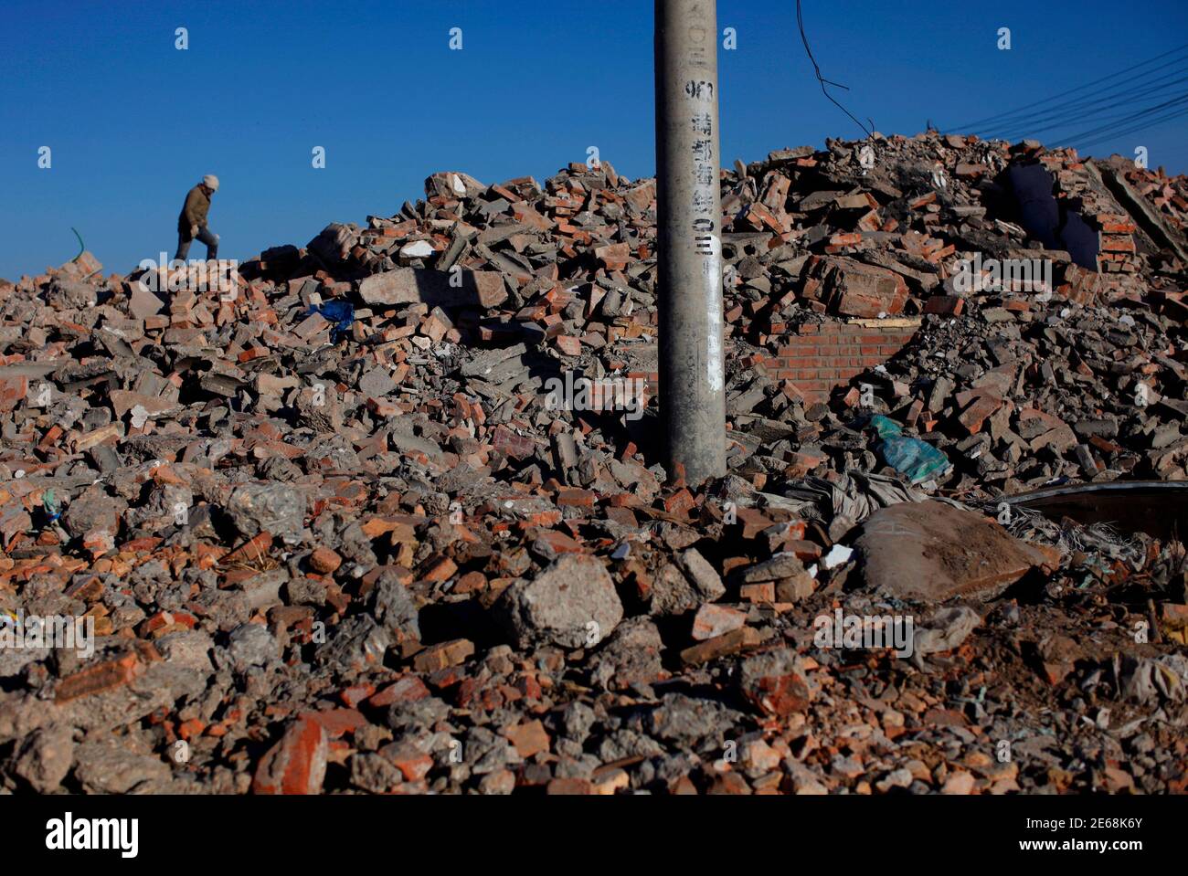 A labourer works at a demolition site to make way for a residential area in Hohhot, Inner Mongolia Autonomous Region, February 15, 2012. China's fledgling real estate investment fund market could see a surge of activity in 2012 as property developers launch their own vehicles in a desperate bid to bridge an estimated $111 billion financing gap in the year ahead. A government-led clampdown on bank, bond, equity and trust market financing for real estate has left developers with little choice other than to set up their own funds, which have raised barely 10 percent of the sum in the past two yea Stock Photo