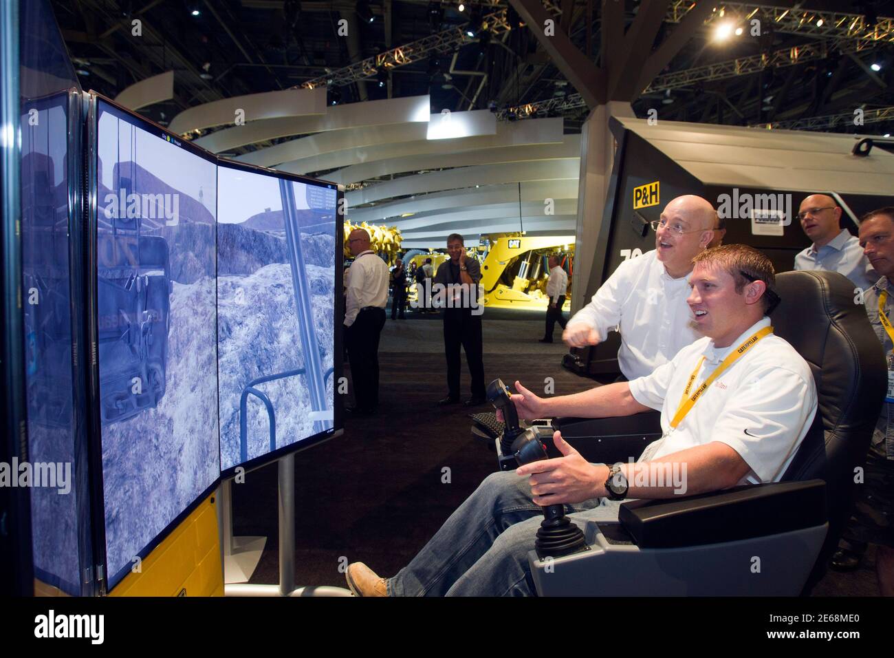 Lee Griffin (C) of JoyGlobal looks on as Michael Hemphill, a maintenance engineer, operates a mining shovel simulator during the MINExpo International 2012 trade show at the Las Vegas Convention Center in Las Vegas, Nevada September 24, 2012. REUTERS/Las Vegas Sun/Steve Marcus (UNITED STATES - Tags: BUSINESS INDUSTRIAL) Stock Photo