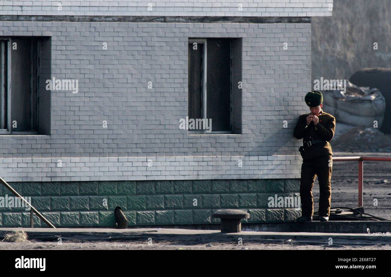 A North Korean soldier leans on a wall along the banks of Yalu River near the North Korean town of Sinuiju, opposite the Chinese border city of Dandong, December 7, 2013. REUTERS/Jacky Chen (NORTH KOREA - Tags: MILITARY) Stock Photo