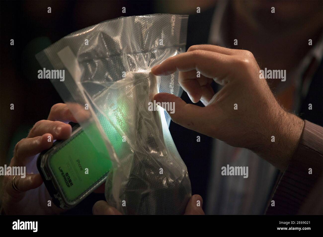 Oenology professor Pierre-Louis Teissedre of the University of Bordeaux inspects the cork from a bottle of wine recovered from a shipwreck using an iPhone for illumination at the Wine + Food Festival in Charleston, South Carolina, March 6, 2015. A bottle of wine recovered intact four years ago from the 1864 wreck of a Civil War blockade runner that sank off the coast of Bermuda was uncorked and sipped by a panel of experts on Friday during the food festival in Charleston, South Carolina. The wine was one of five sealed bottles recovered by marine archaeologists from the Mary-Celestia, an iron- Stock Photo
