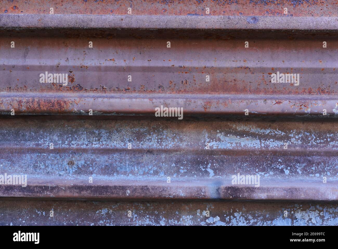 Sheet of metal rusty texture with traces of purple paint faint color ...