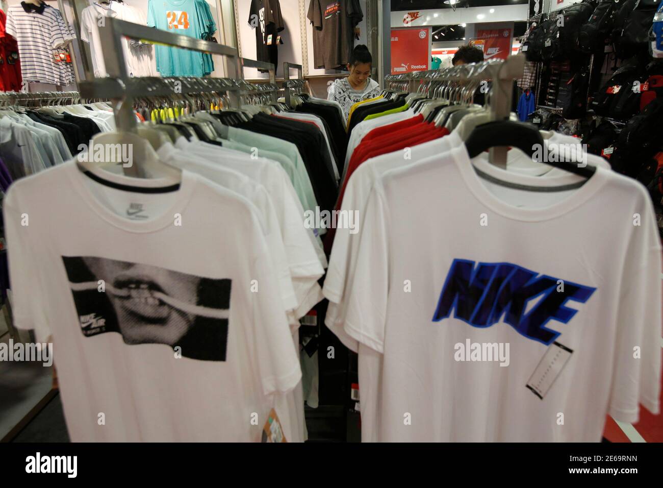 A salesperson arranges Nike T-shirts inside a shop at a shopping district  in Beijing, August 6, 2013. China's home-grown sportswear industry is  finally showing signs of recovery after nearly two years of