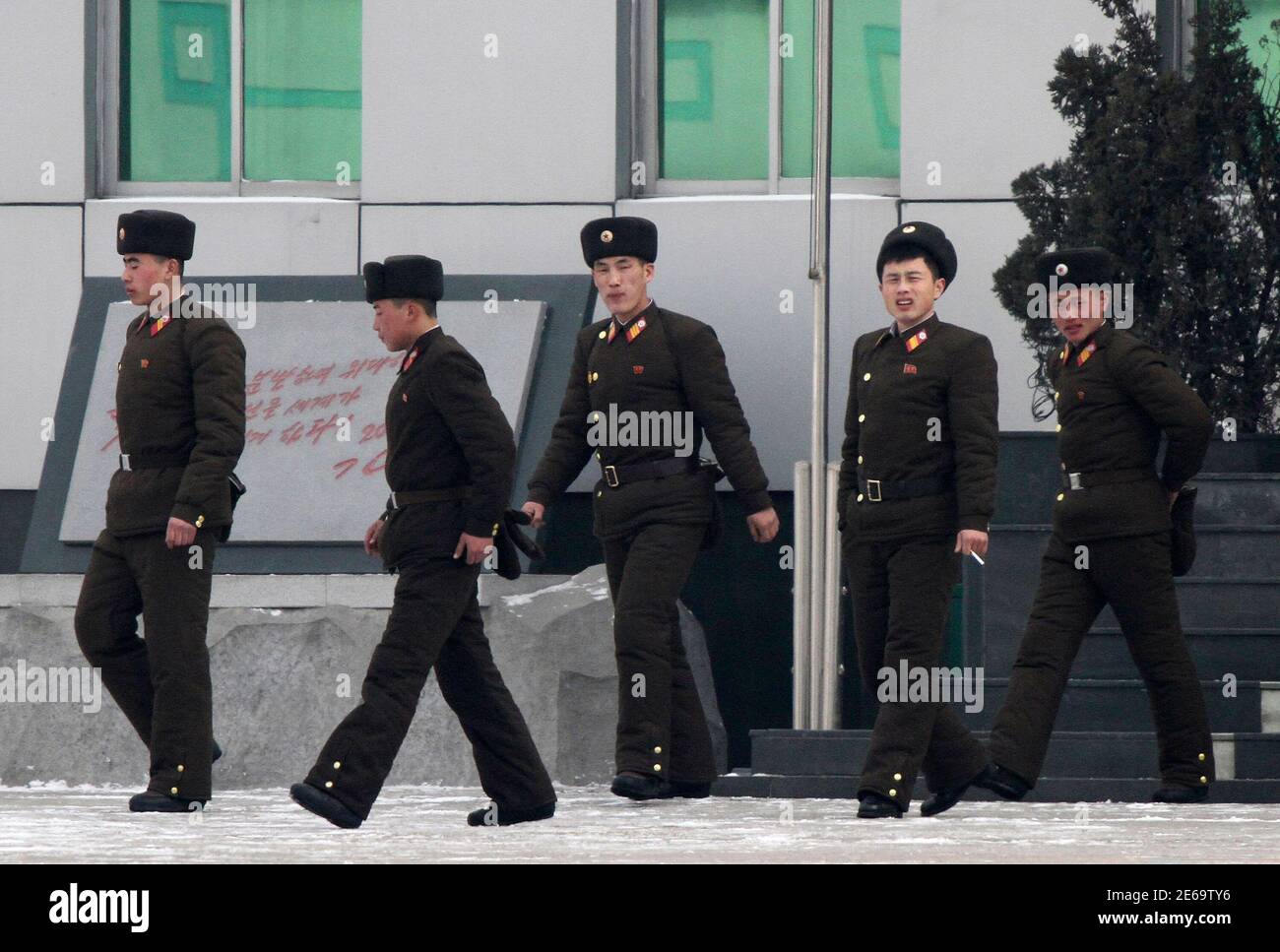 North Korean soldiers walk in front of a building on the banks of Yalu River, near the North Korean town of Sinuiju, opposite the Chinese border city of Dandong, January 20, 2014. North Korea demanded that South Korea and the United States halt annual military drills due in February and March, saying they were a direct provocation, a statement that suggested a re-run of a sharp escalation in tension last year. REUTERS/Jacky Chen (NORTH KOREA - Tags: MILITARY POLITICS) Stock Photo