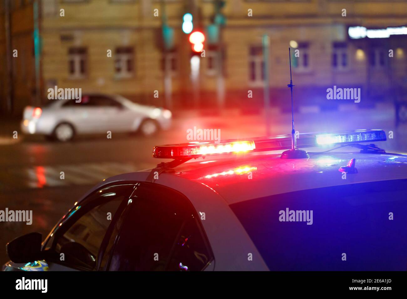 police car lights in street with civilian car in blurry background at night in european city Stock Photo