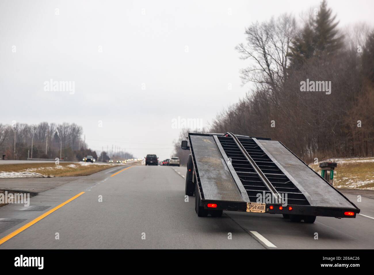 A truck pulling an empty car carrier trailer changes lanes on US 31 on a gloomy Indiana Winter day. Stock Photo