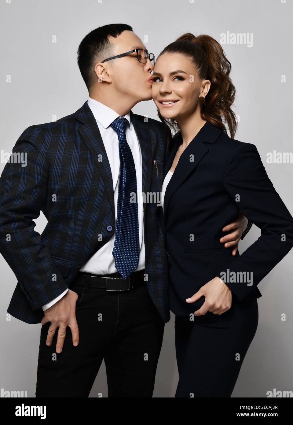 Young couple man and woman in love business professionals office workers in  formal suits hug each other and kissing Stock Photo