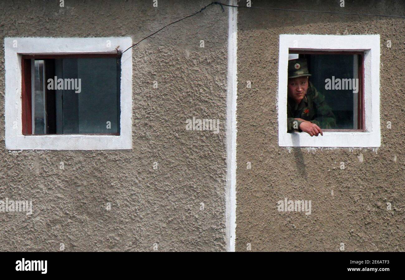 A North Korean soldier looks out from a window of a guard tower on the banks of the Yalu River, near the North Korean town of Sinuiju, opposite the Chinese border city of Dandong, June 21, 2014. Picture taken June 21, 2014. REUTERS/Jacky Chen (NORTH KOREA - Tags: MILITARY SOCIETY) Stock Photo