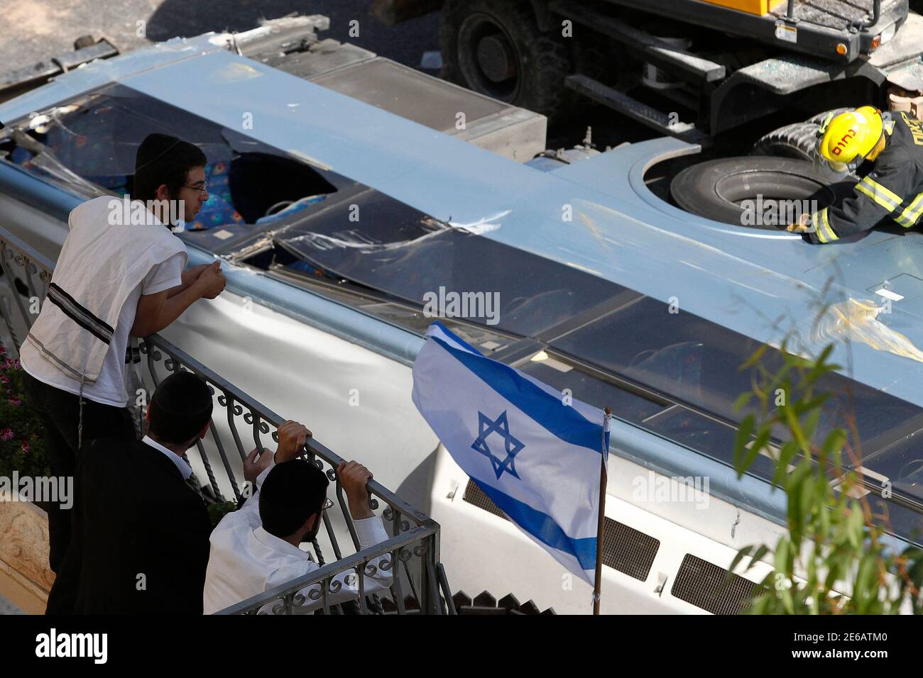 Residents look at an overturned bus at the scene of a suspected attack in Jerusalem August 4, 2014. A Palestinian used his heavy construction vehicle to run down and kill an Israeli and overturn the bus on a main Jerusalem street on Monday in attacks that ended when policemen shot him dead, police said. REUTERS/Siegfried Modola (JERUSALEM - Tags: POLITICS CIVIL UNREST) Stock Photo