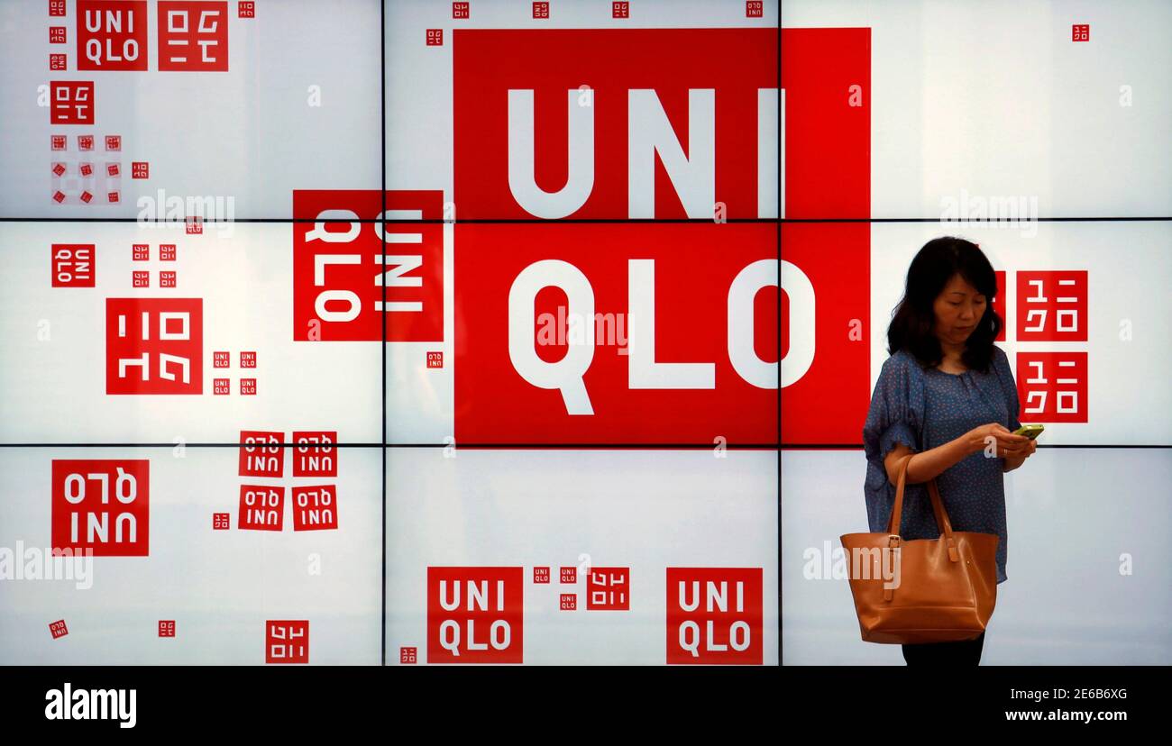 A woman checks her phone in front of a panel outside the flagship store of  Japanese fashion house Uniqlo at Hong Kong's Causeway Bay shopping district  May 9, 2013. Armed with empty