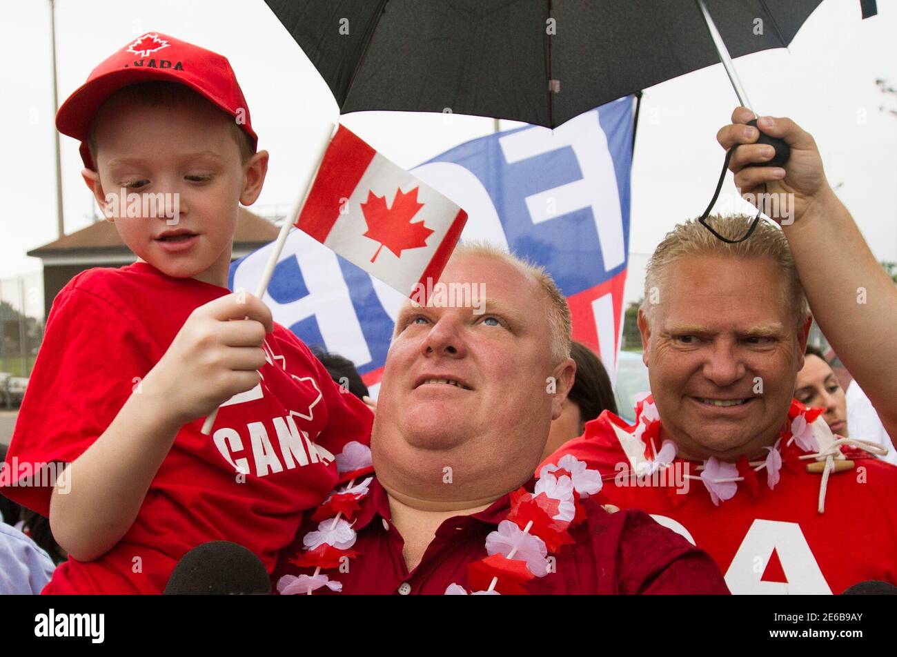 Toronto Mayor Rob Ford Holds A Boy In In Front Of His Brother Doug (R) As  They Take Part In The East York Canada Day Parade, The Mayor's First Public  Appearance Since