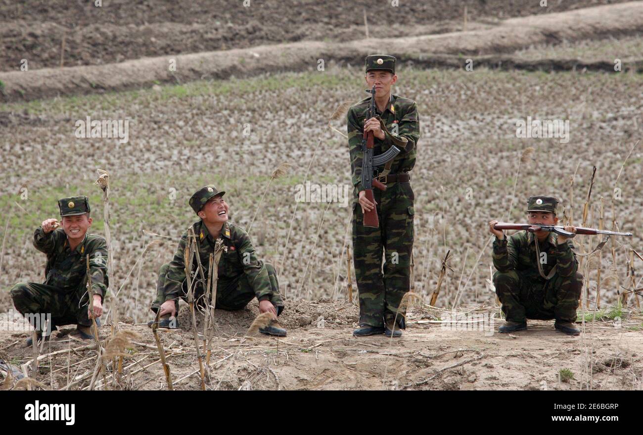 Armed North Korean soldiers joke with Chinese tourists as they keep guard at Hwanggumpyong Island, near the North Korean town of Sinuiju and the Chinese border city of Dandong, May 1, 2012. The United States, South Korea, Japan and European nations have submitted to the U.N. Security Council's North Korea sanctions committee lists of individuals and firms they want blacklisted after Pyongyang's recent rocket launch, envoys said on Monday. REUTERS/Jacky Chen (NORTH KOREA - Tags: MILITARY POLITICS SOCIETY CIVIL UNREST) Stock Photo