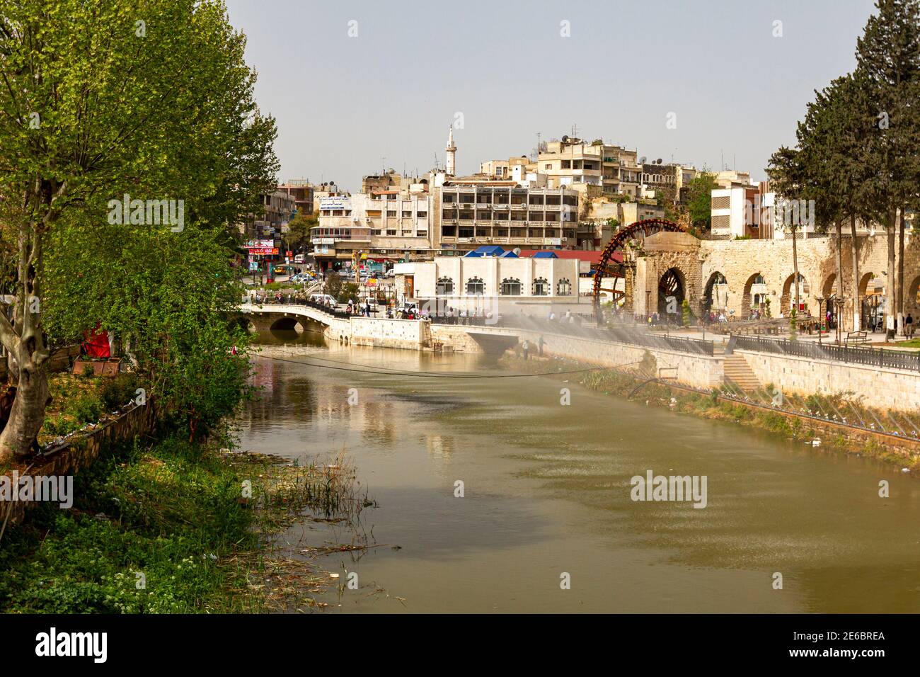 Hama, Syria 04-02-2010: cityscape featuring the Orontes river and arched stone bridge over it. There are historic aqueducts on banks of river as well Stock Photo