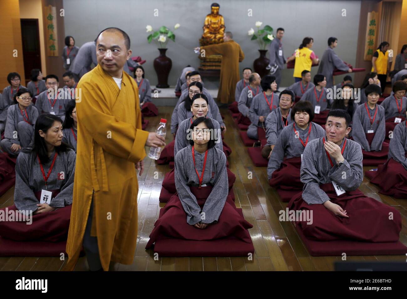 A Buddhist monk stands in front of participants attending a class at Yufo Buddhism Temple in Shanghai, China, July 8, 2015. About 70 Shanghai residents took part in the two-day 'zen' class at the temple on Wednesday, which required them to lock away their mobile phones, tablet devices and other belongings so that they could concentrate on the study of Buddhism. Over 500 people has signed up for these classes which are organised by the temple for free, local media reported. REUTERS/Aly Song TPX IMAGES OF THE DAY Stock Photo