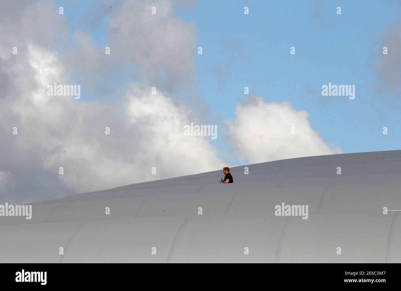 A worker stands on the roof of the Olympic water polo arena in Olympic Park, Stratford, east London, July 19, 2012. The 2012 London Olympic Games will begin in just over a week.  REUTERS/Andrew Winning (BRITAIN - Tags: SPORT OLYMPICS) Stock Photo