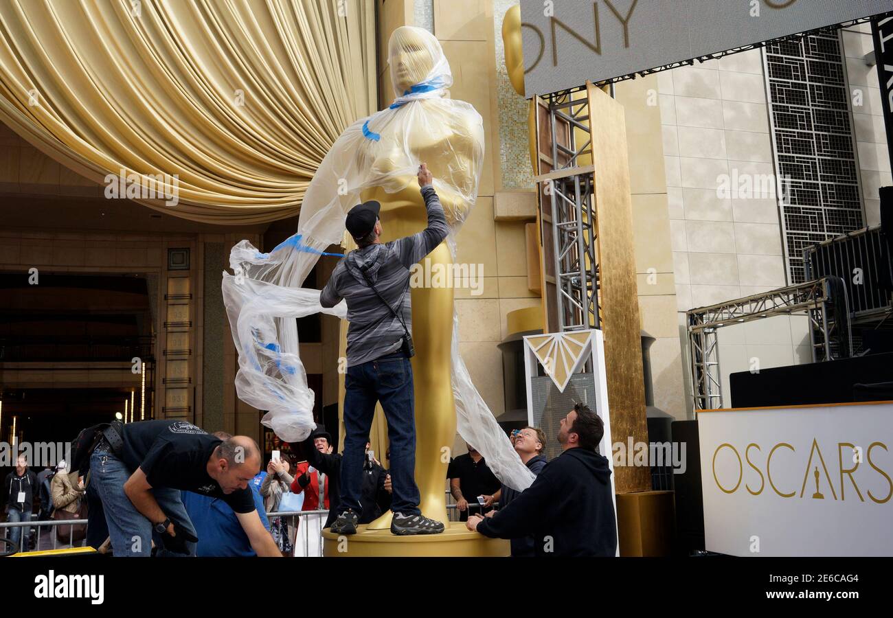 A carpenter removes protective plastic from an Oscar statue just placed outside the Dolby Theater during preparations for the 87th Academy Awards in Hollywood, California February 20, 2015. The Oscars will be presented at the Dolby Theater February 22, 2015.   REUTERS/Rick Wilking  (UNITED STATES - Tags: ENTERTAINMENT) Stock Photo