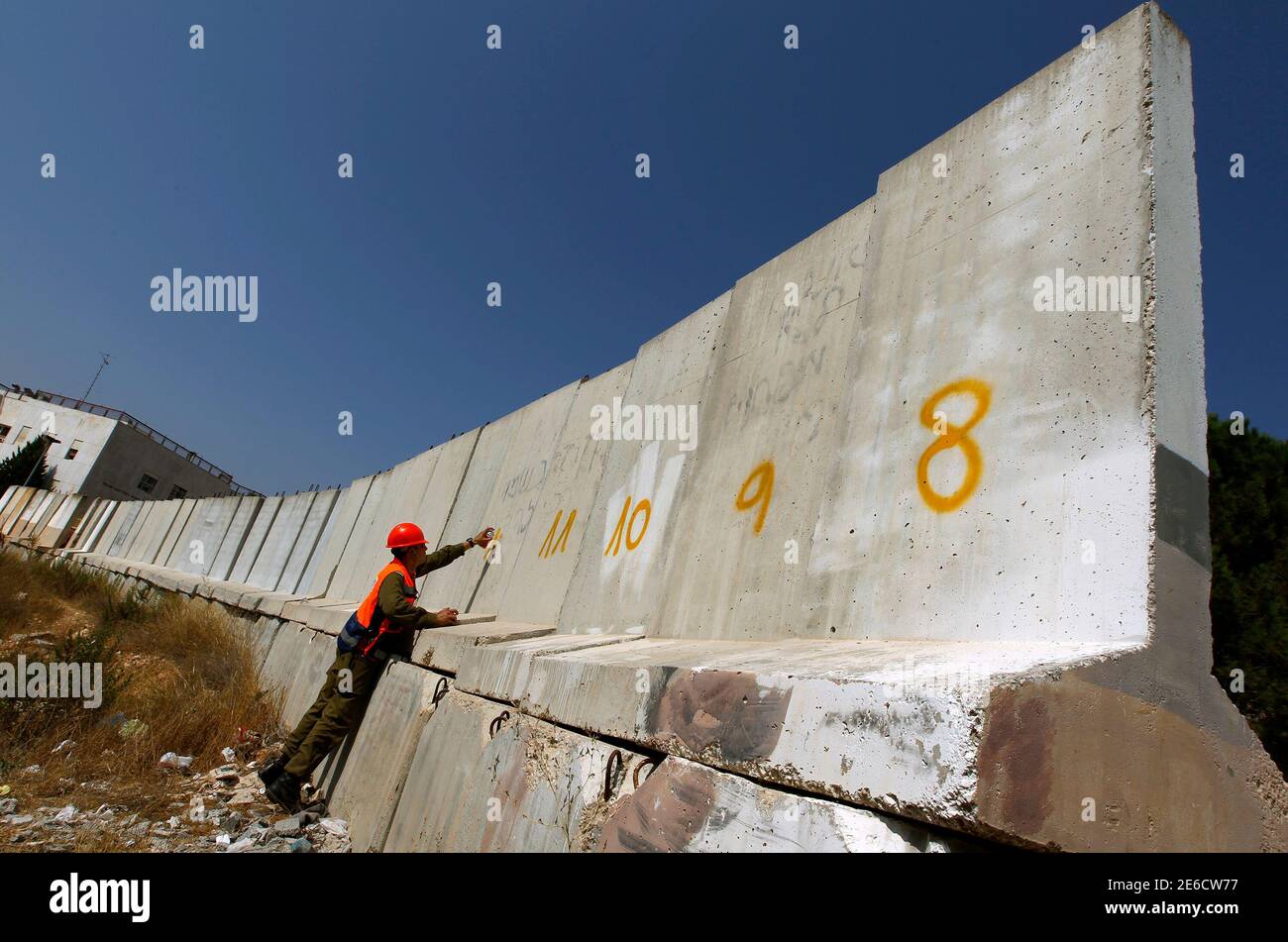 An Israeli soldier spray paints a number on a section of a concrete wall in Gilo, a Jewish settlement on land Israel captured in 1967 and annexed to its Jerusalem municipality before it is removed August 15, 2010. In a sign of improved stability in the West Bank, Israel is removing the concrete blast walls put up eight years ago to shield the settlement on Jerusalem's outskirts from Palestinian gunfire and shells.  REUTERS/Baz Ratner (POLITICS CIVIL UNREST) Stock Photo