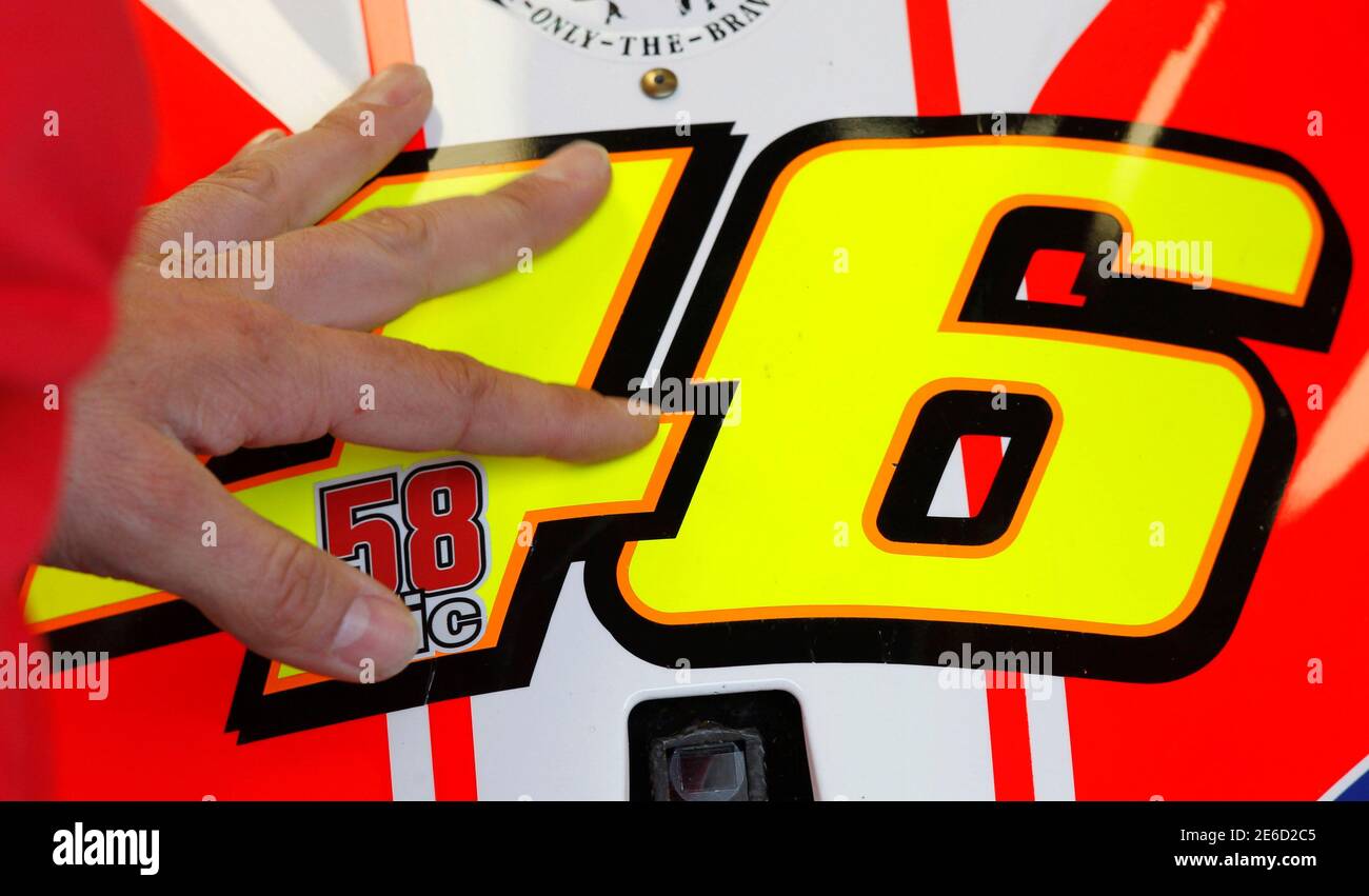 A mechanic touches the motorbike of Italian Ducati MotoGP rider Valentino  Rossi, bearing the number 58, a number that Honda MotoGP rider Marco  Simoncelli of Italy previously used, during the first free