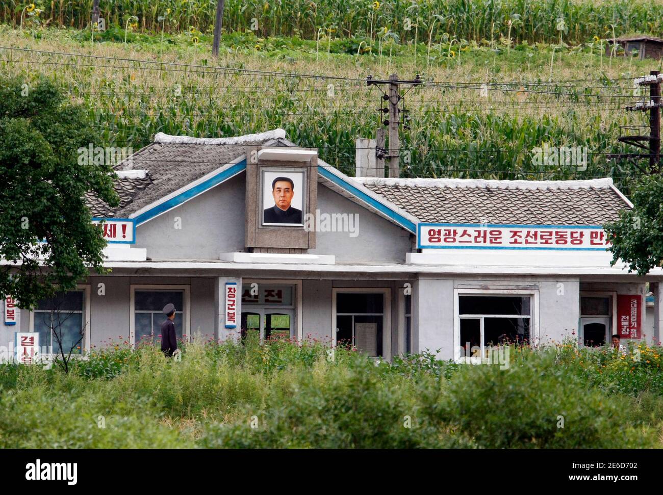 A railway worker looks up at a portrait of late North Korean leader Kim Il-Sung at a railway station in Hoeryong, North Hamgyong province August 28, 2013. Picture taken August 28, 2013. REUTERS/Jacky Chen (NORTH KOREA - Tags: SOCIETY TRANSPORT) Stock Photo