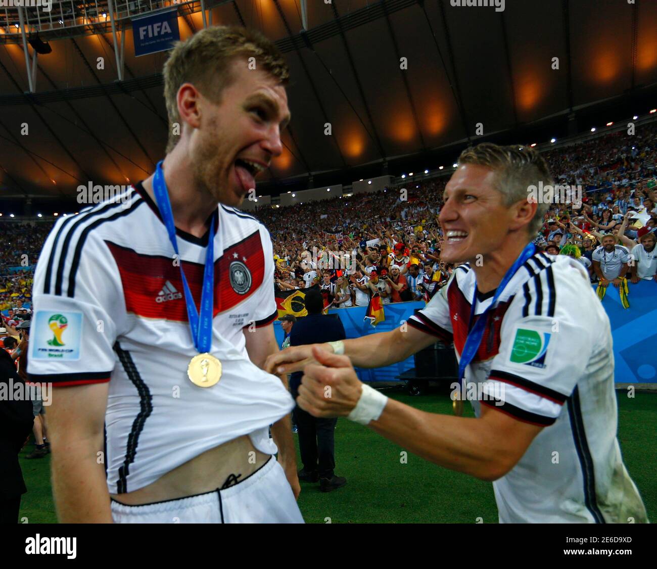 Germany's Per Mertesacker (L) celebrates with Bastian Schweinsteiger after  winning their 2014 World Cup final against Argentina at the Maracana  stadium in Rio de Janeiro July 13, 2014. REUTERS/Eddie Keogh (BRAZIL -