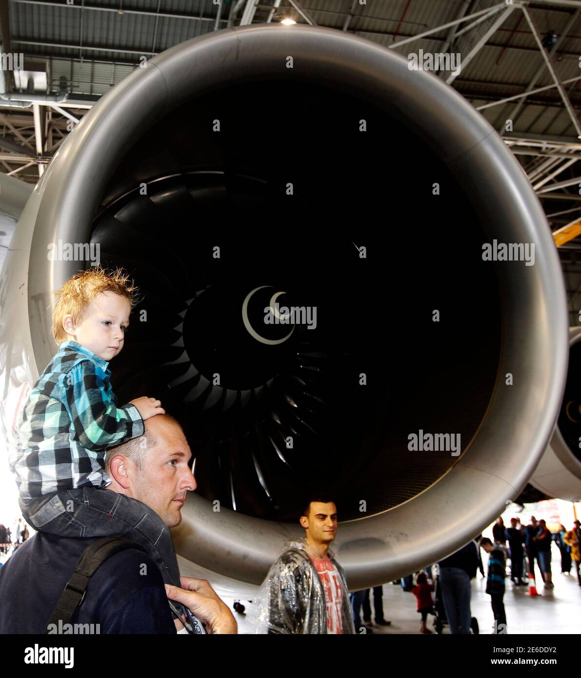 A Qantas employee and his son wait to have their picture taken next to one of the engines of a Qantas A380 during Qantas' 90th anniversary celebrations at Sydney Airport November 6, 2010. Engine trouble forced QF6 a Qantas Airways Ltd Boeing 747-400 jet to make an emergency landing in Singapore on Friday, less than 48 hours after another of the Australian carrier's aircraft had to land prematurely because its engine blew up. REUTERS/Daniel Munoz (AUSTRALIA - Tags: TRANSPORT ANNIVERSARY) Stock Photo