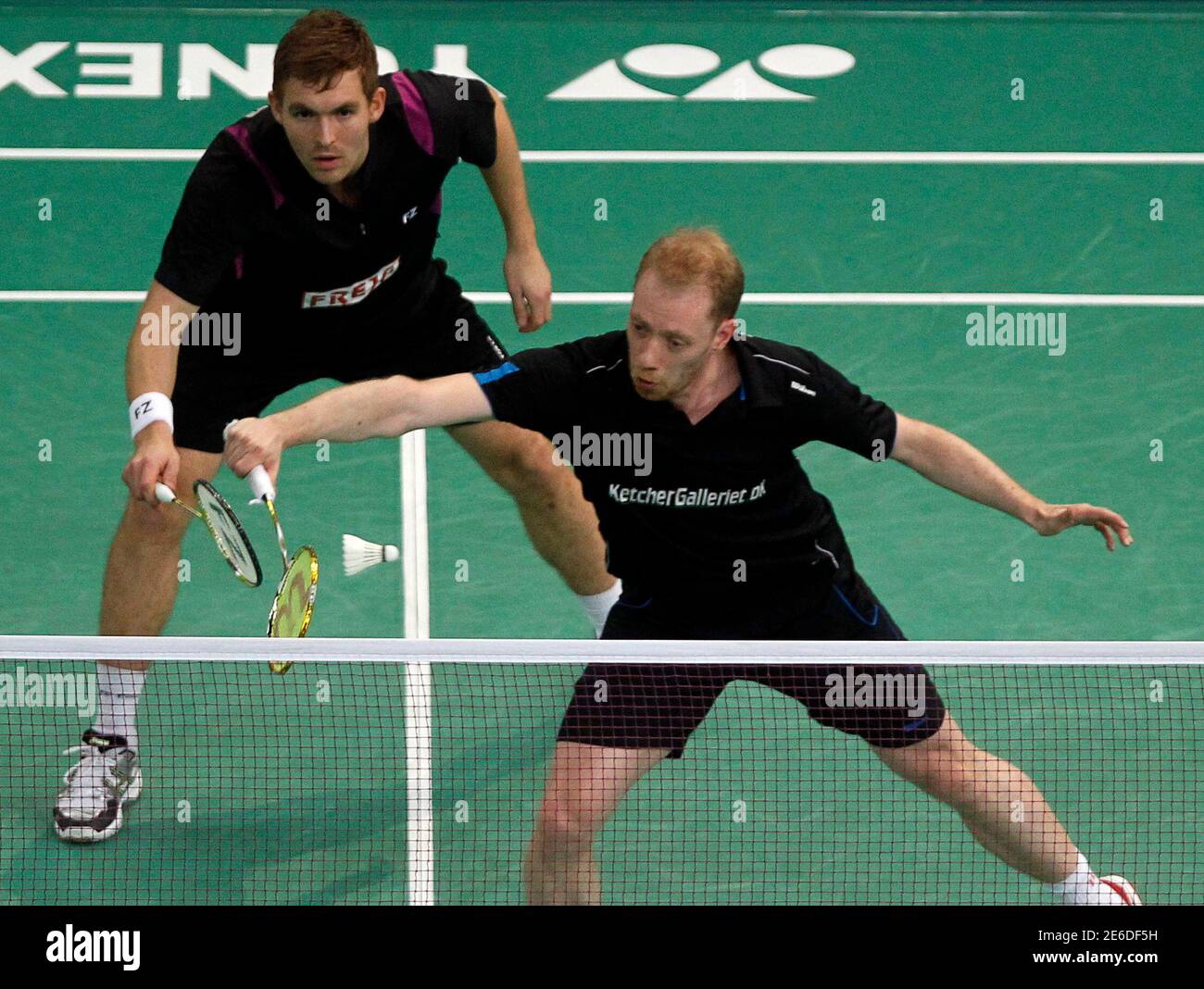 Denmark's Jonas Rasmussen hits a return as teammate Mads Conrads-Petersen  looks on during their match against China's Guo Zhendong / Chai Biao in the  men's doubles finals of Malaysian Open Super Series