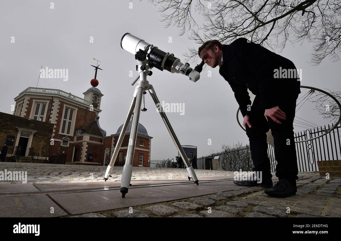 Astronomer Brendan Owens poses with a refractive telescope on the Meridian  line at The Royal Observatory in Greenwich, south east London March 19,  2015. A full solar eclipse will occur on March