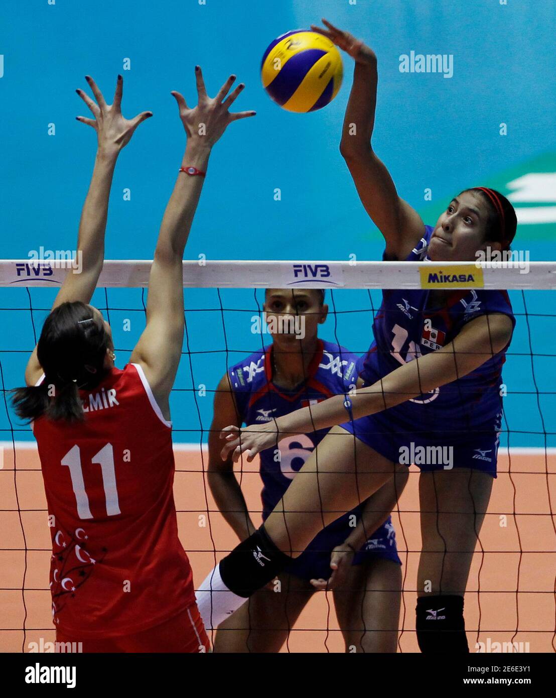 Peru's Karla Ortiz (R) spikes the ball against Turkey's Naz Aydemir (11)  while Peru's Jessenia Uceda looks on during their second round match of the  FIVB Women's Volleyball World Championship in Tokyo