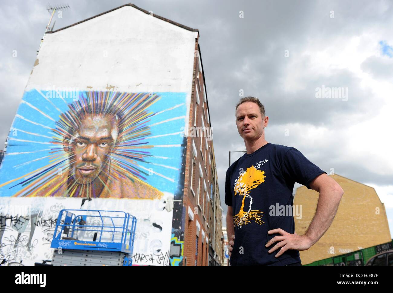 Street artist James Cochran, also known as Jimmy C, poses near his spray painted picture of Jamaican sprinter Usain Bolt in Sclater street car park in east London July 19, 2012. Cochran said this was done as an homage to the London 2012 Olympic Games, which begin July 27. REUTERS/Paul Hackett  (BRITAIN - Tags: SPORT OLYMPICS ATHLETICS ENTERTAINMENT) Stock Photo