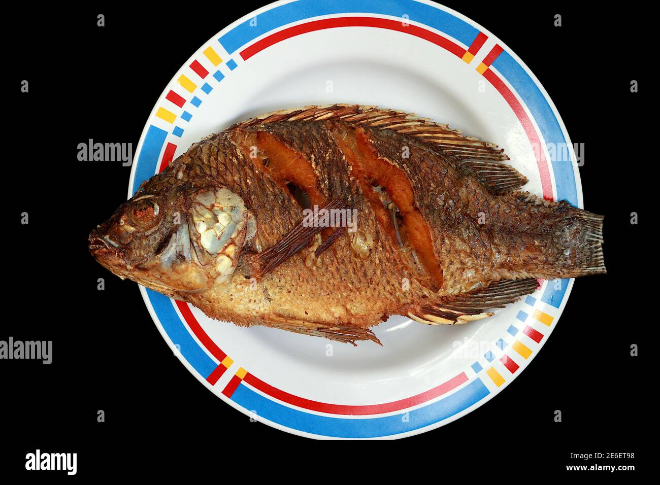 One of the fried tilapia on a plate. On a black background Stock Photo Alamy