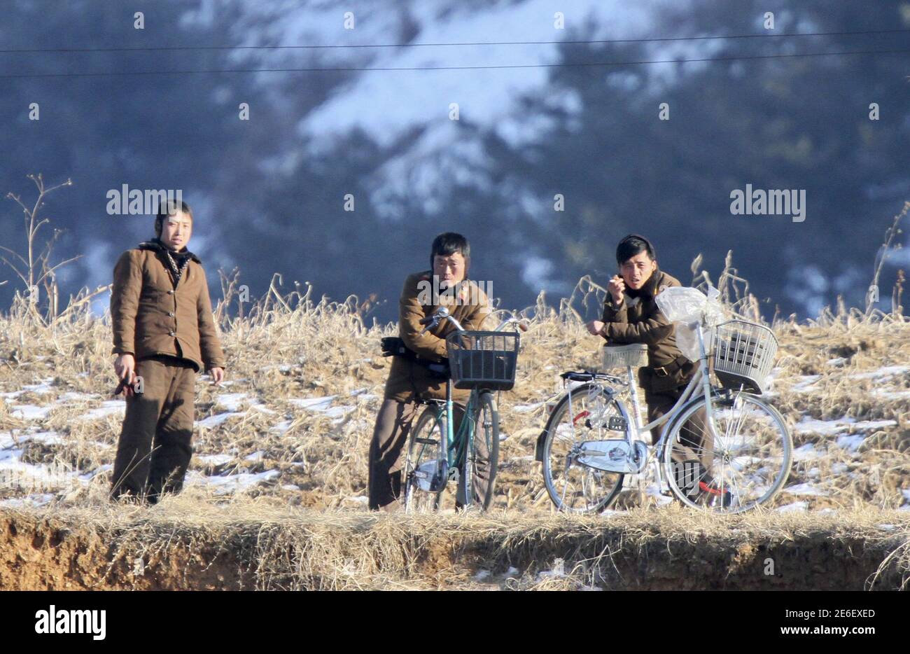 Members of North Korean military rest on their bicycles on the banks of Yalu River, in Sakchu county, North Korea, January 7, 2016. REUTERS/Jacky Chen      TPX IMAGES OF THE DAY Stock Photo