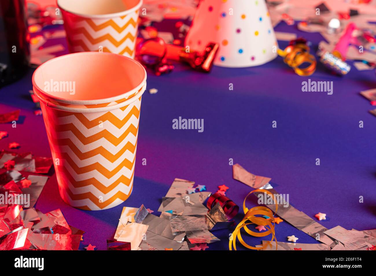 Party tinsel and colorful cups close up on purple background Stock Photo