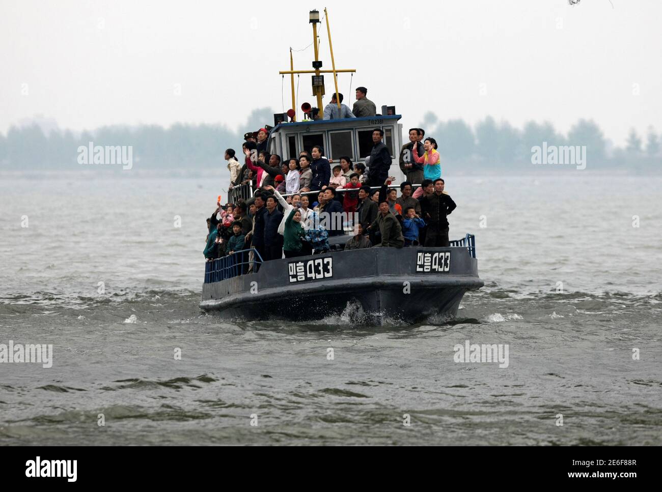 North Korean tourists wave during their tour on the Yalu River in Sinuiju, near the Chinese border city of Dandong, May 1, 2016. Picture taken from China's side of the Yalu. REUTERS/Jacky Chen Stock Photo