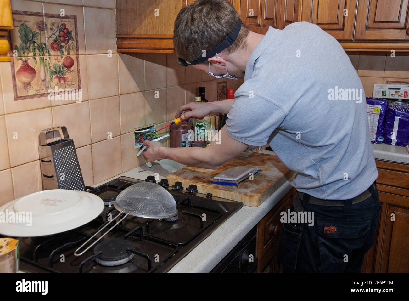 Electrician Refitting And Testing A New Plug Socket In A Kitchen Wall Electrician Refitting And Testing A New Plug Socket In A Kitchen Wall
