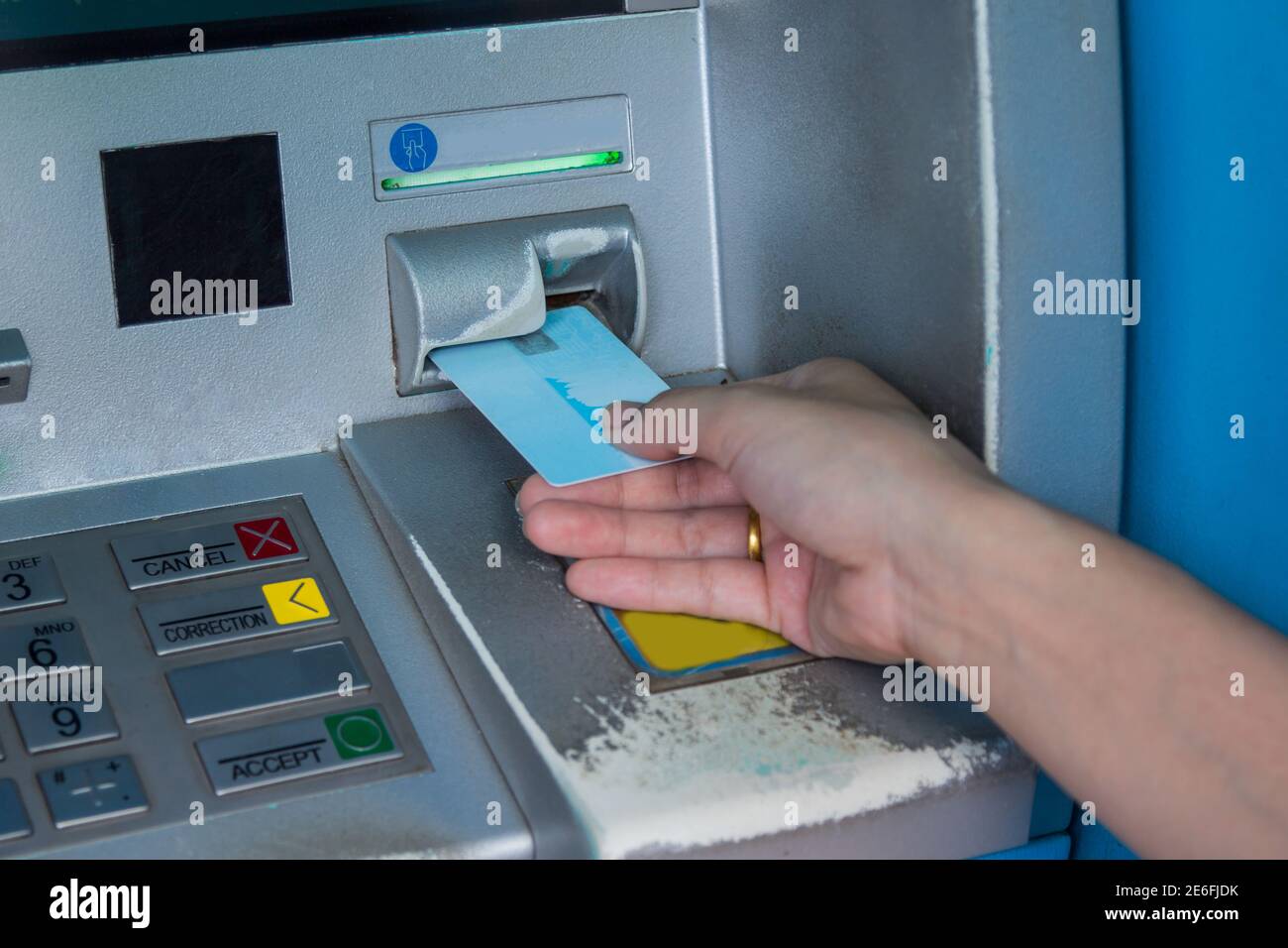 Hand inserting ATM credit card into bank machine to withdraw money Stock Photo