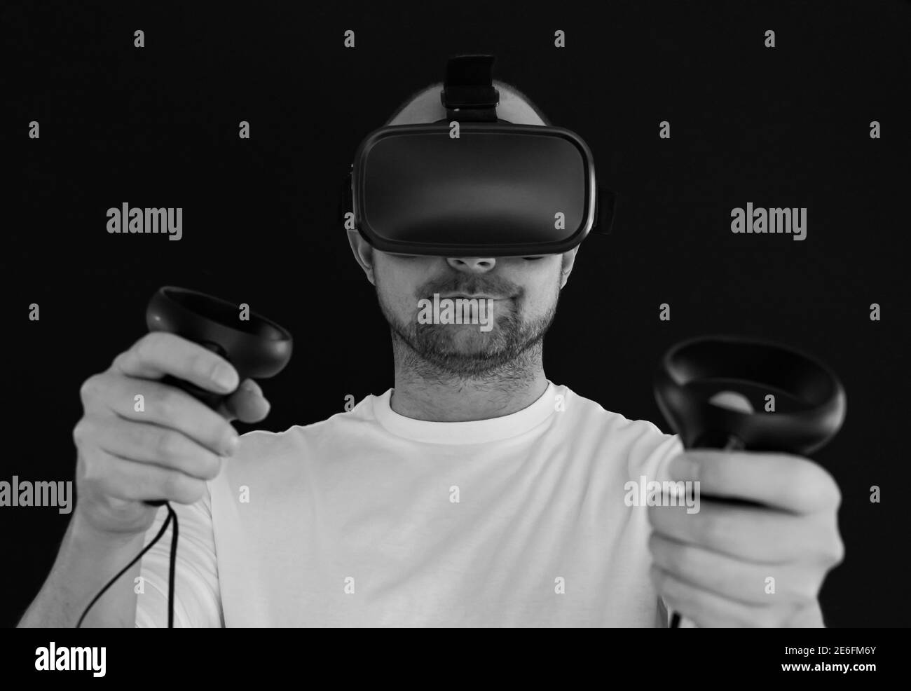 Man wearing VR headset and using hand controllers in virtual reality. Stock Photo
